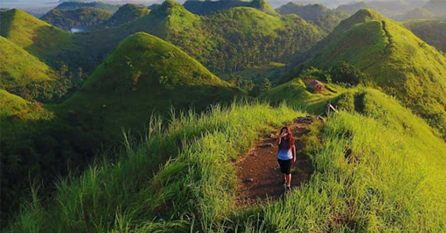 A photo of a woman on top of a hill.